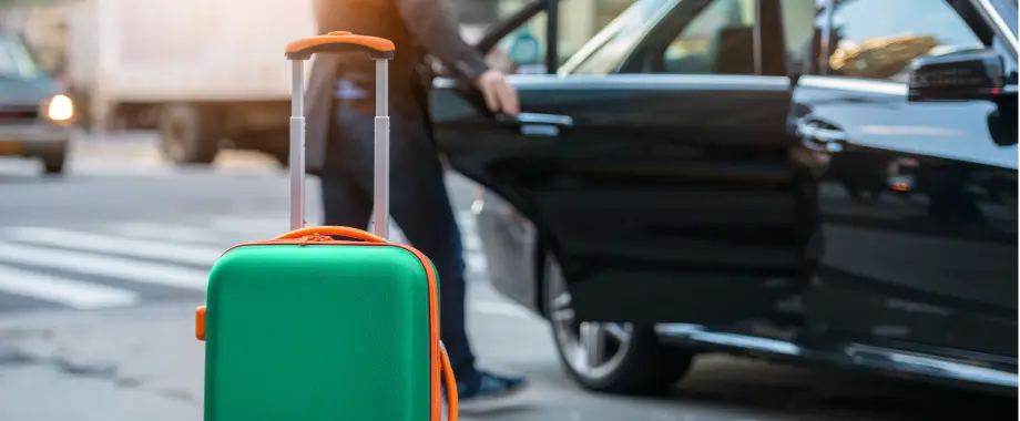 Green suitcase waiting to be loaded in a taxi