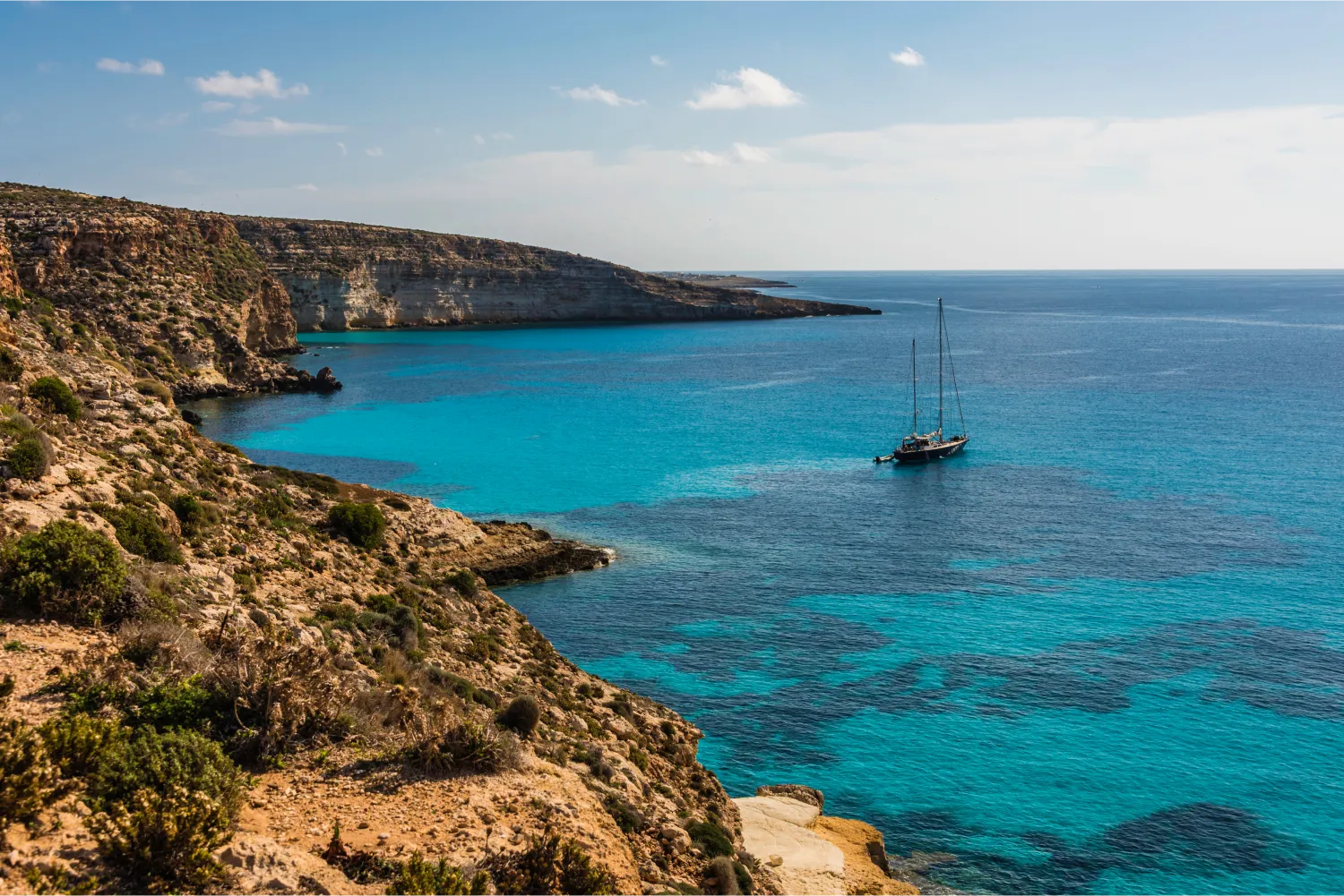 The extraordinary Rabbit Beach In Lampedusa and a sailing boat departing