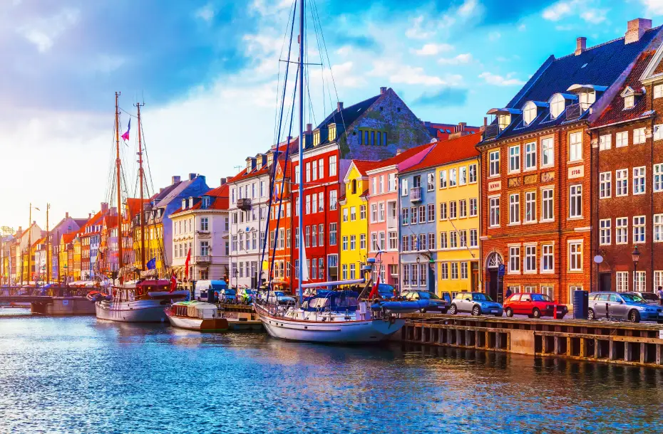 View of sunset at the Old Town of Copenhagen, Denmark, with boats parked at the harbor, in front of colorful buildings