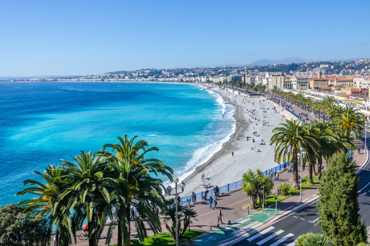 Aerial view Of The Bay Of Angels in Nice. Pine trees and people walking and sunbathing on the shore