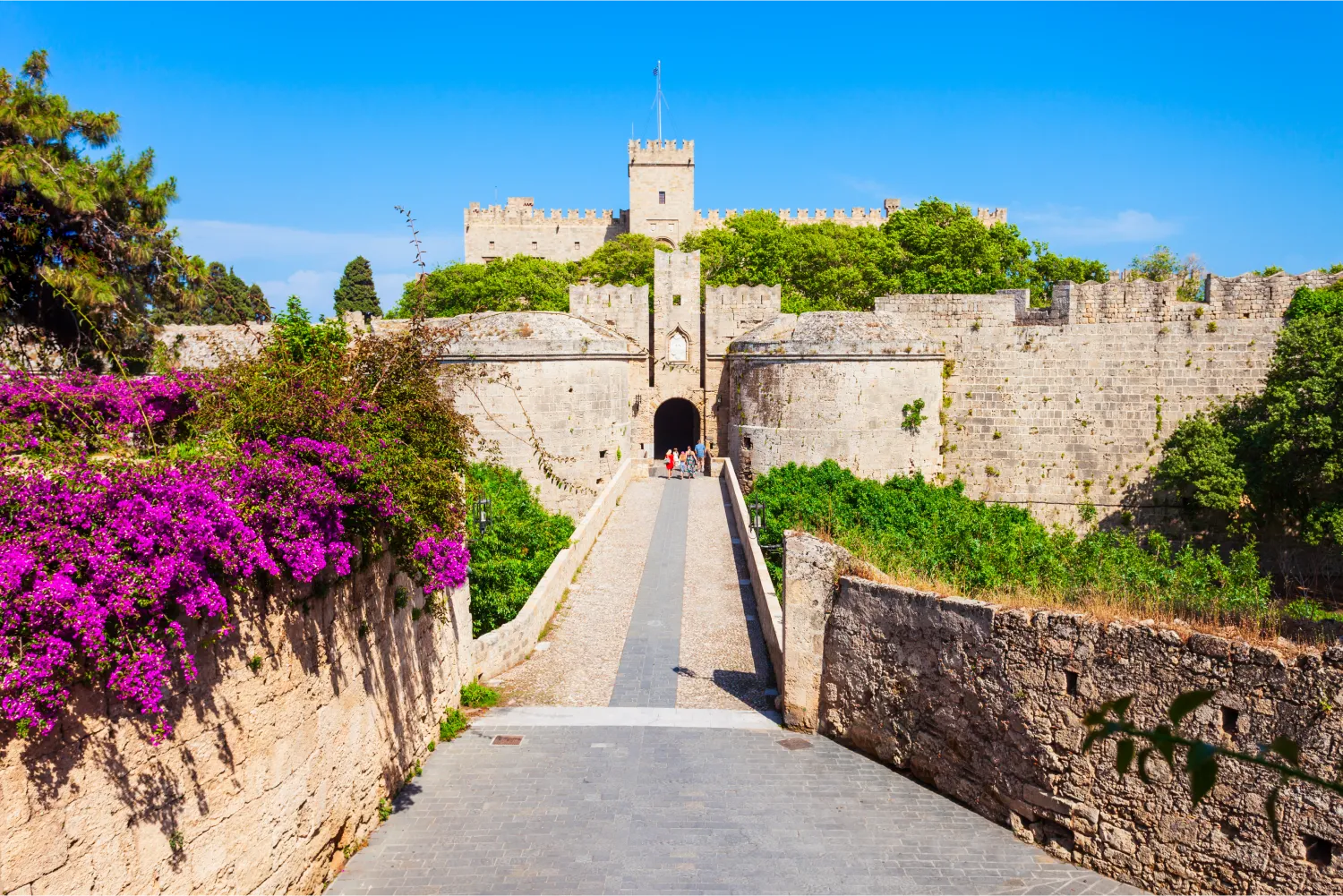 The way to the dominating castle of Rhodes with flowers and lush vegetation around
