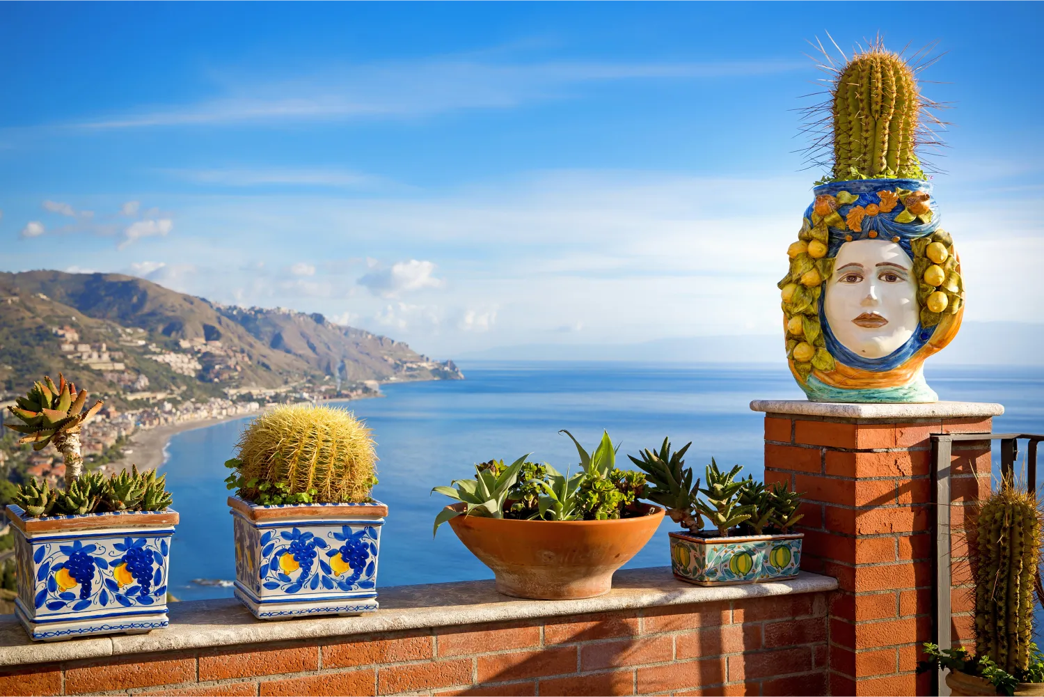 flower pots on a balcony in Sicily and Beautiful View Of The Coastline Taormina in the background