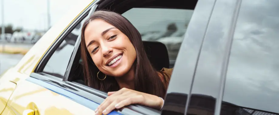 Happy woman looking outside taxi's window