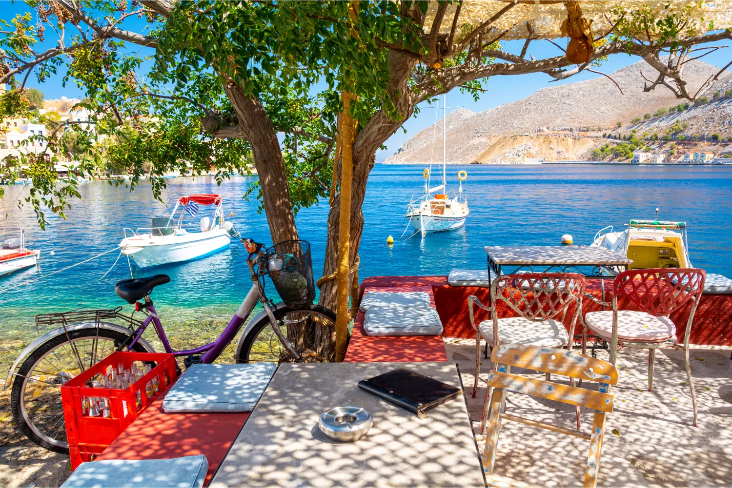 A bicycle parked in a colorful cafe next to the fishing port of Symi