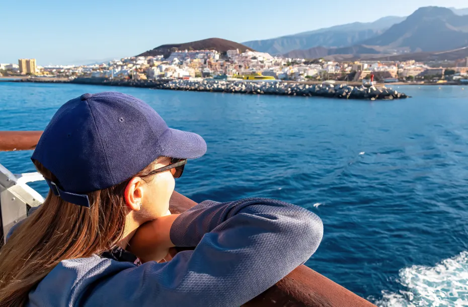 Woman with cap, overlooking a Greek port from a ship's open deck