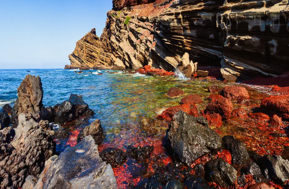 View of Punta Calcarella Beach in Linosa. A volcanic rocky beach with diverse colors