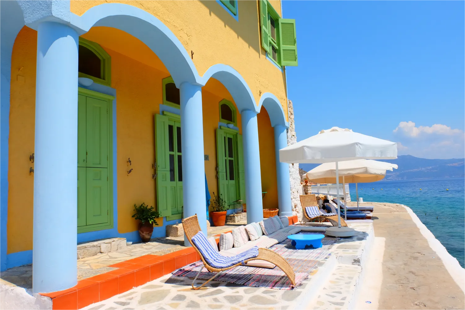 Sunbeds in front of colorful building overlooking the sea in Megisti, Kastelorizo